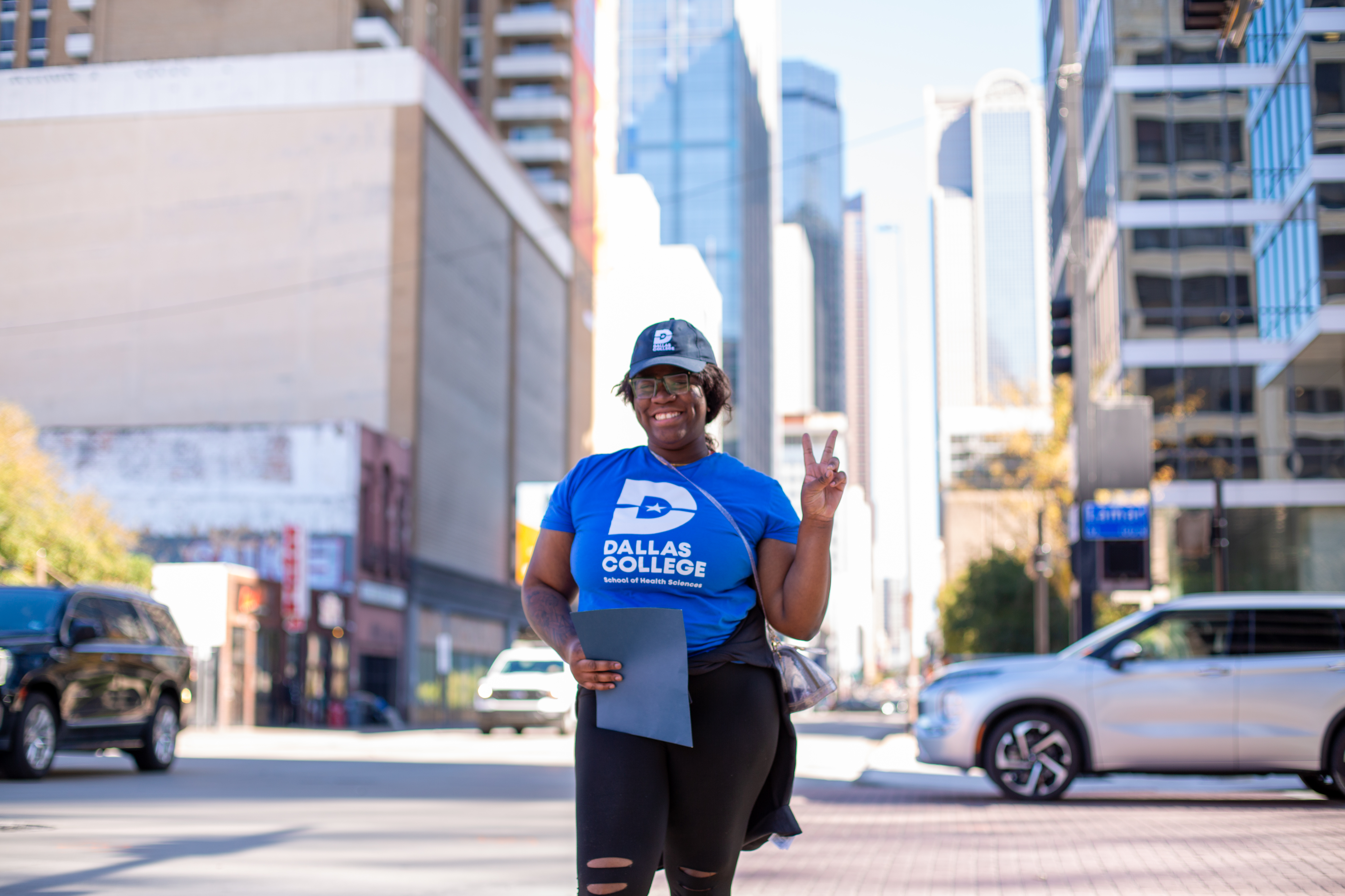 Dallas College student standing in downtown Dallas with the skyline behind her