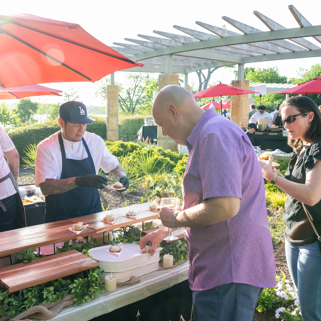 Two Bits and Bites patrons at a chef's booth grabbing a bite of food