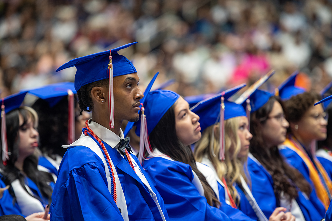 Dallas College graduate sitting at graduation ceremony looking up at stage