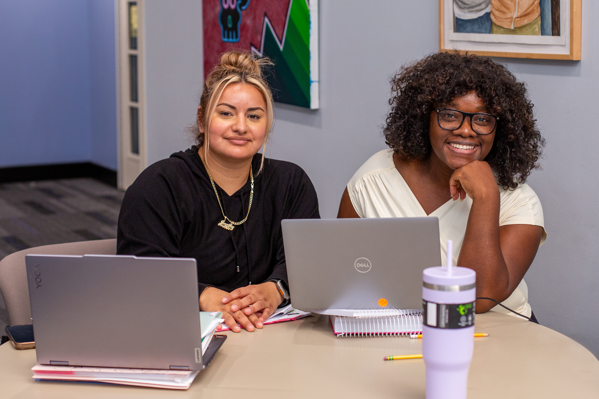 Two students with their laptops studying inside of a Dallas College campus at a table