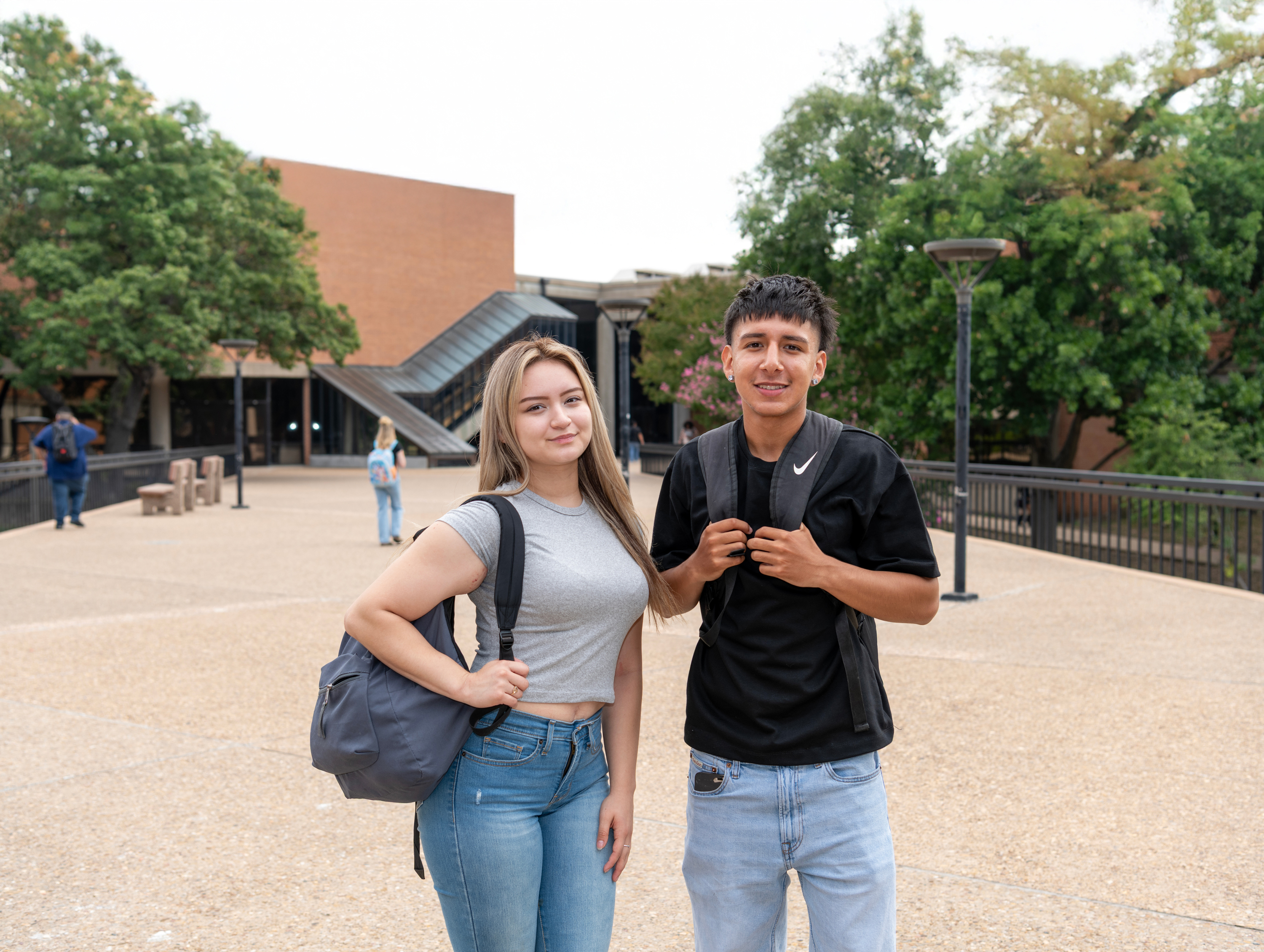 Two students on Dallas College campus standing outside in front of building