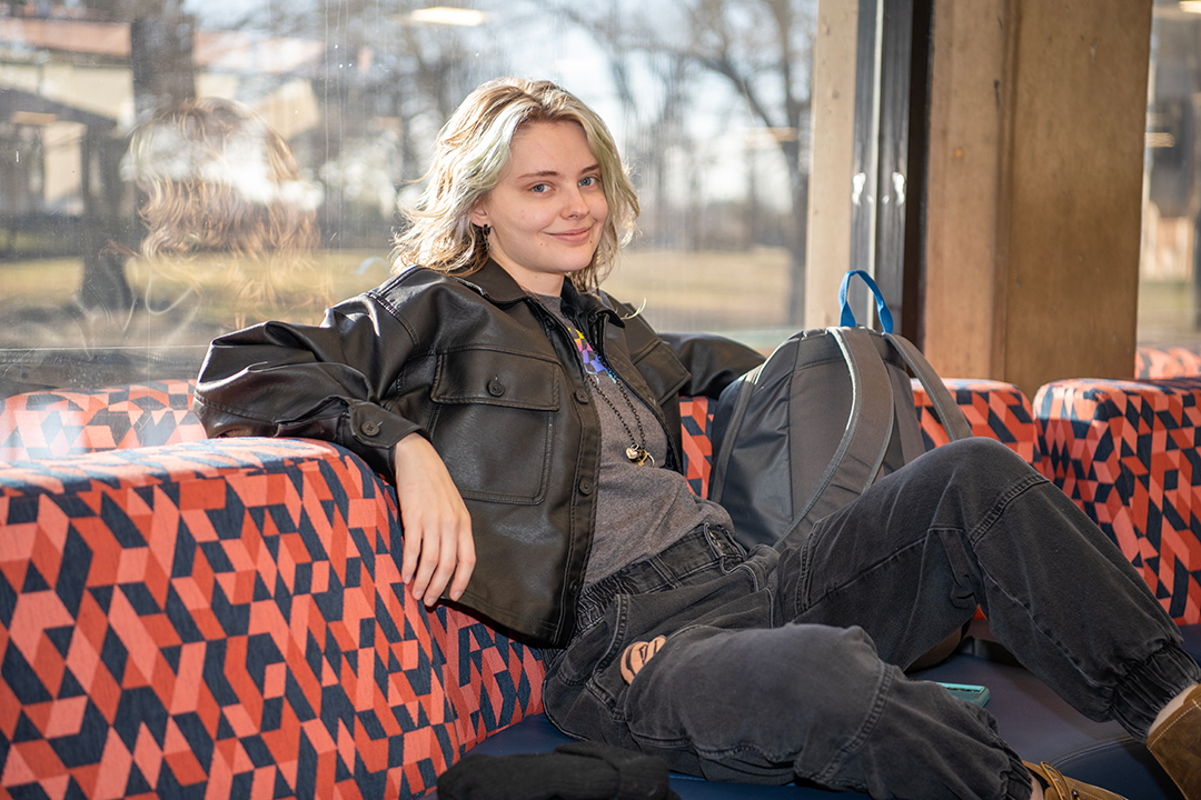 Dallas College student sitting on a seat on campus and smiling
